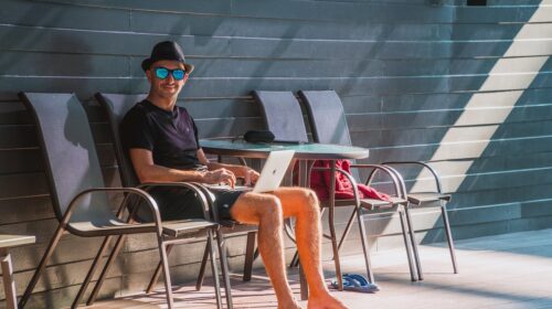 Digital Nomads Read This for Tips on How to Work While Adventuring - Man with a Laptop by a Pool How to Keep Your Business Running While You Travel
