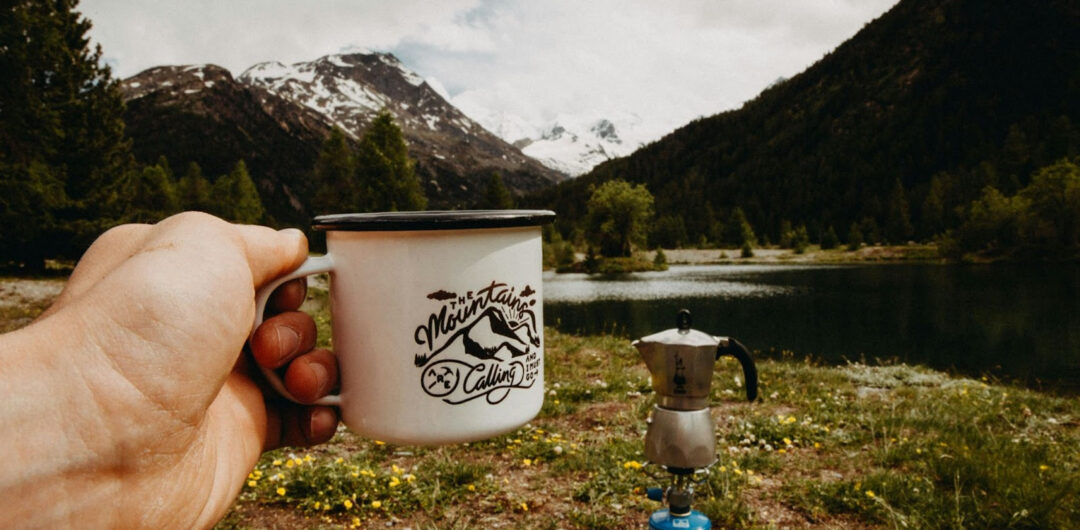 6 Different Ways of Camping for Every Kind of Camper - Hand Holding Out Mug by a Lake