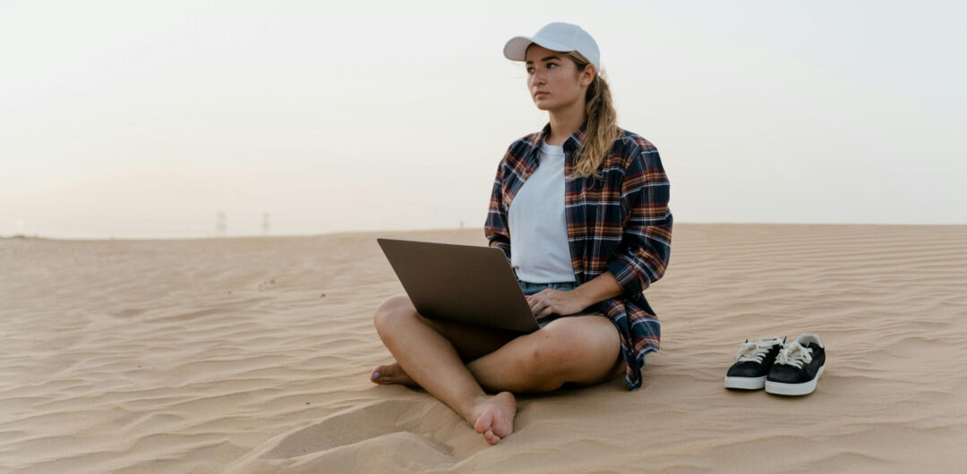 How to Keep Your Business Running While You Travel - Woman on Laptop on a Beach