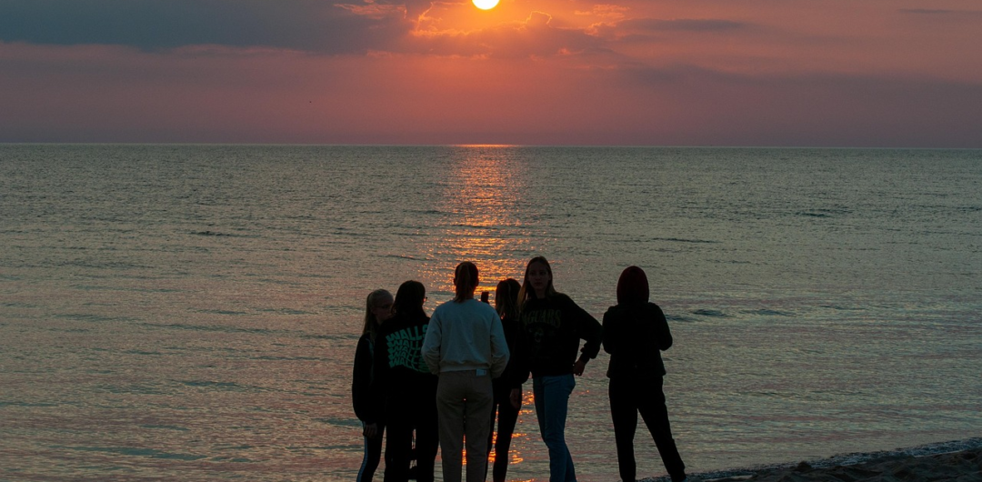 4 Ways Matching Gear Makes Group Trips Better - Group Watching Sunset on a Beach